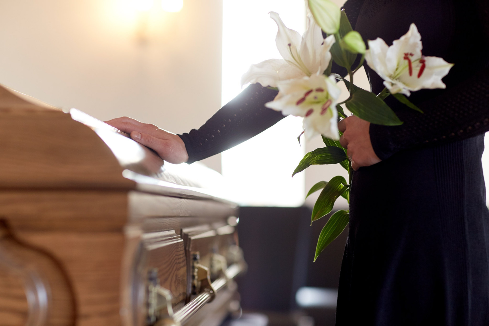 Mourner placing white lilies on a casket