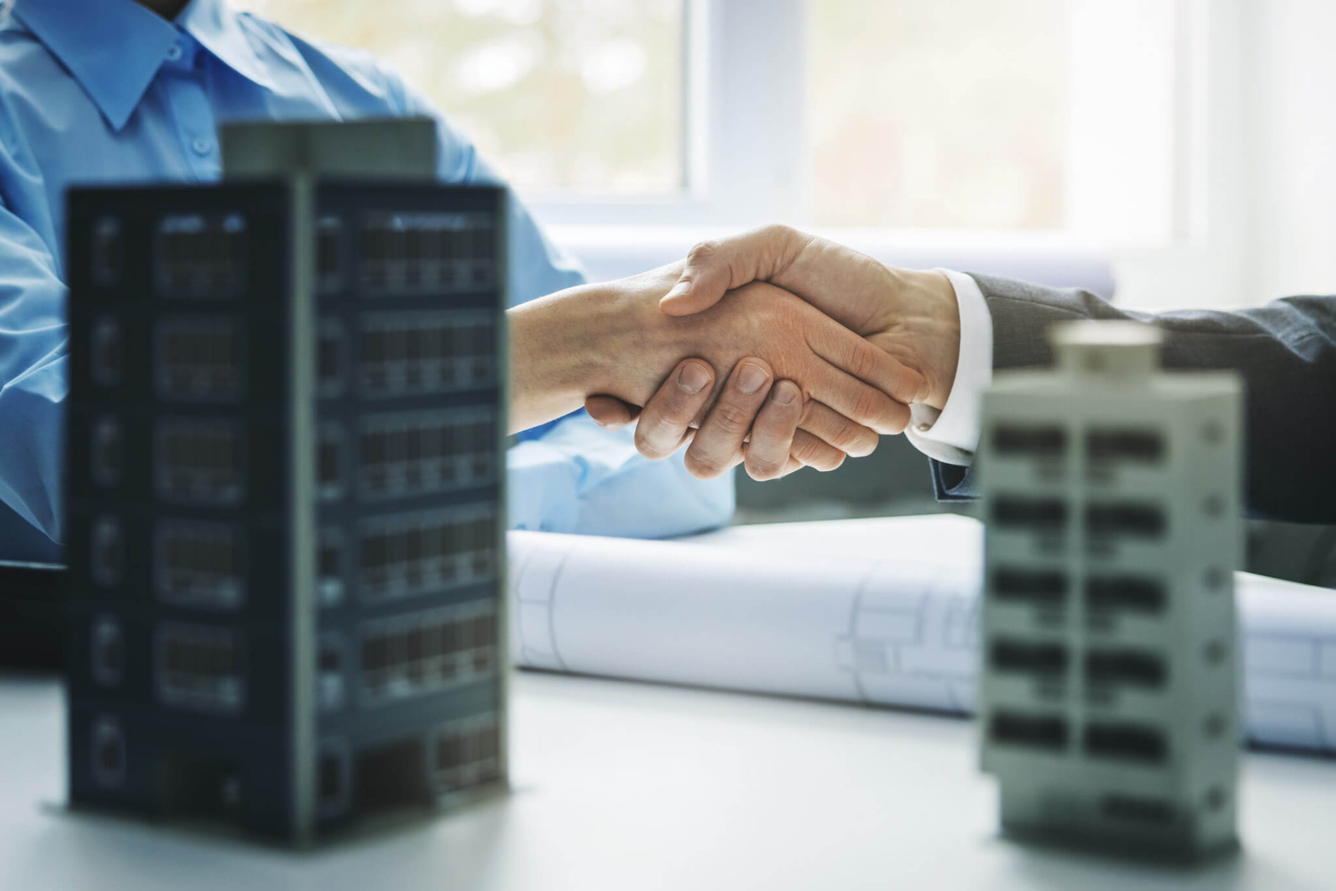 Business handshake over building models and blueprints