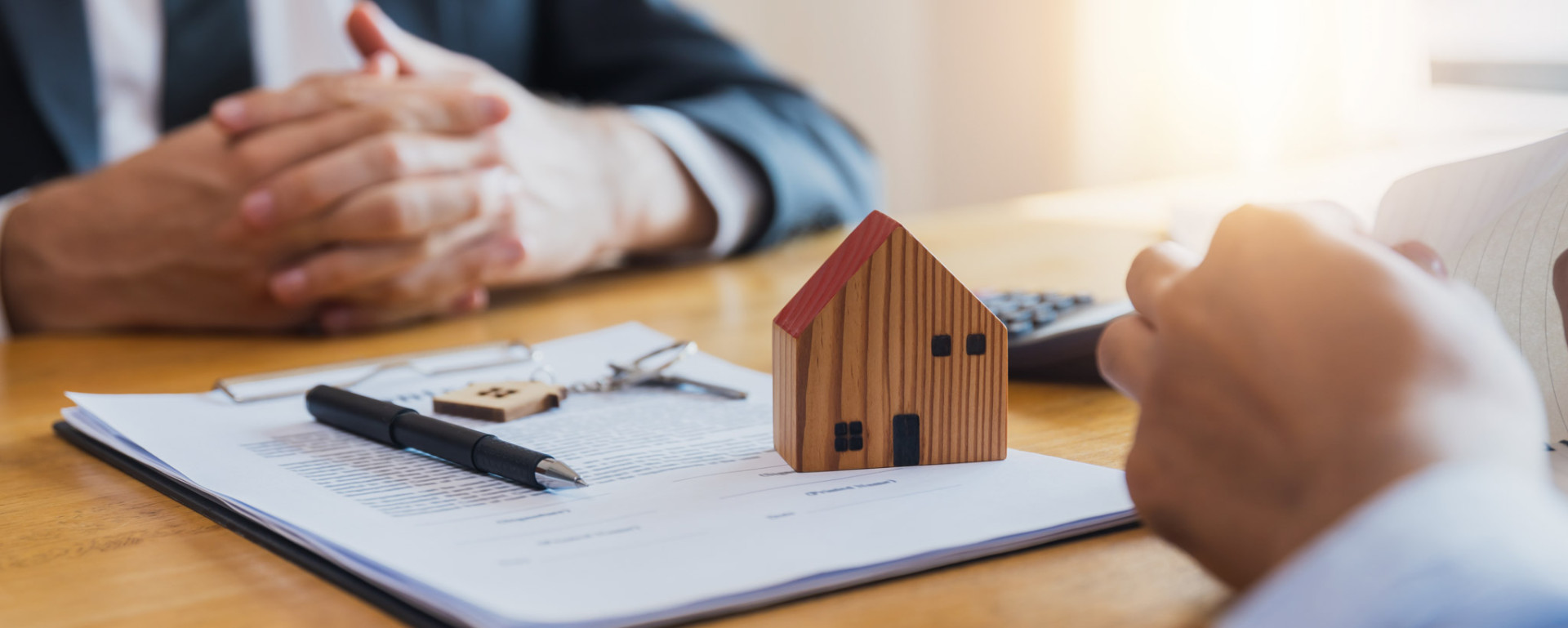 Clients reviewing a property agreement beside a model house