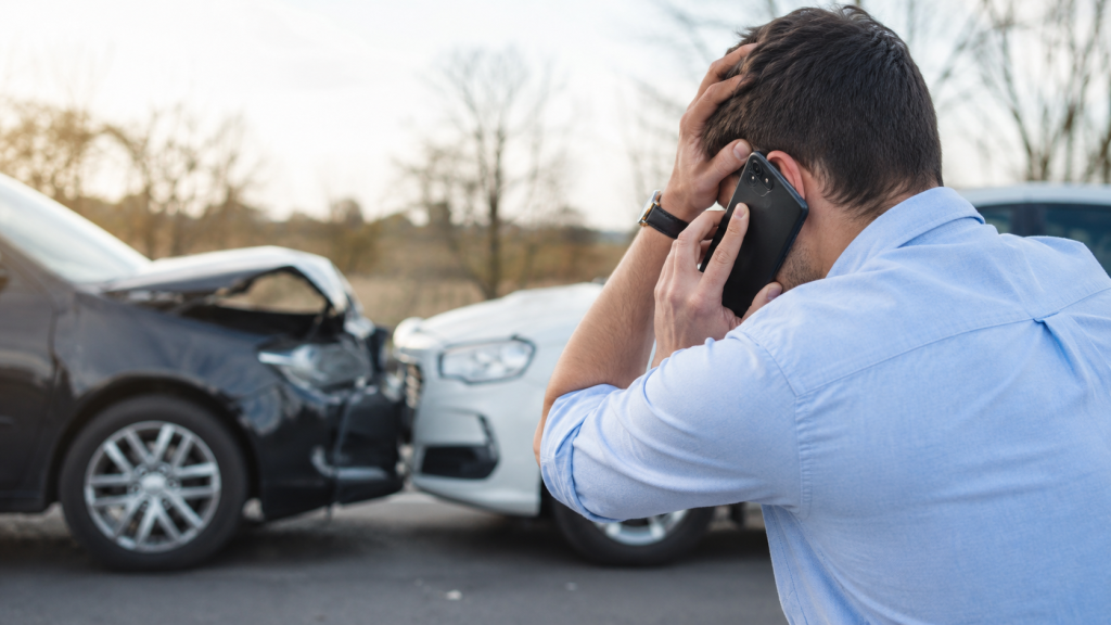 Man on the phone beside two damaged cars