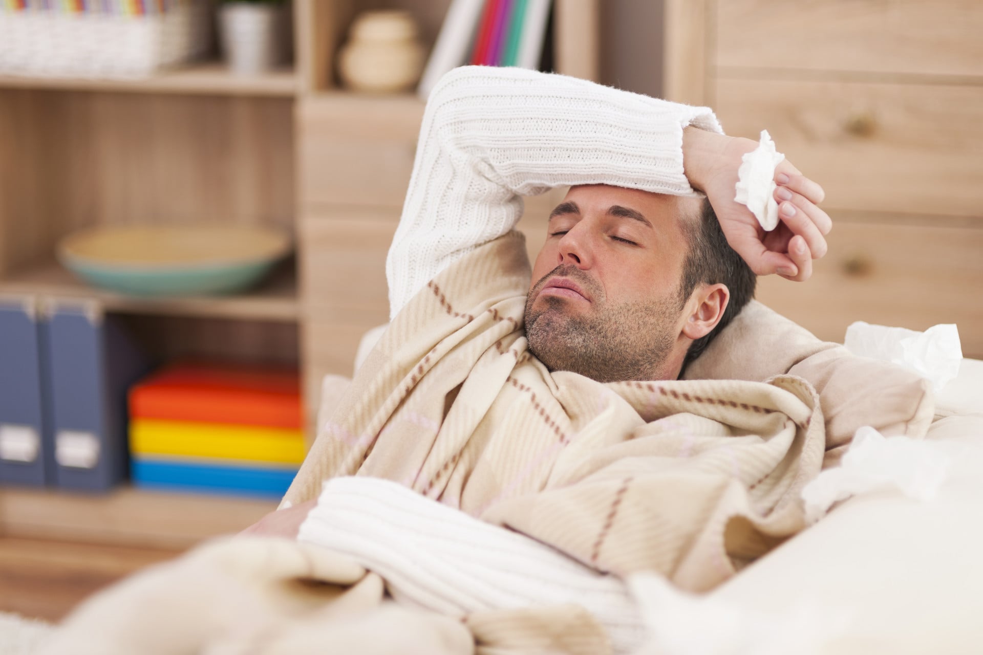 Sick man lying on a couch with a cold compress