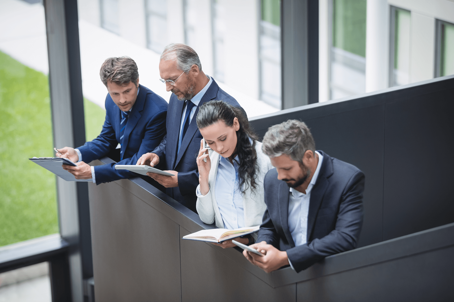 Business professionals using phones and tablets on office stairs
